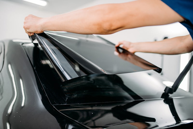 man applying car window tint