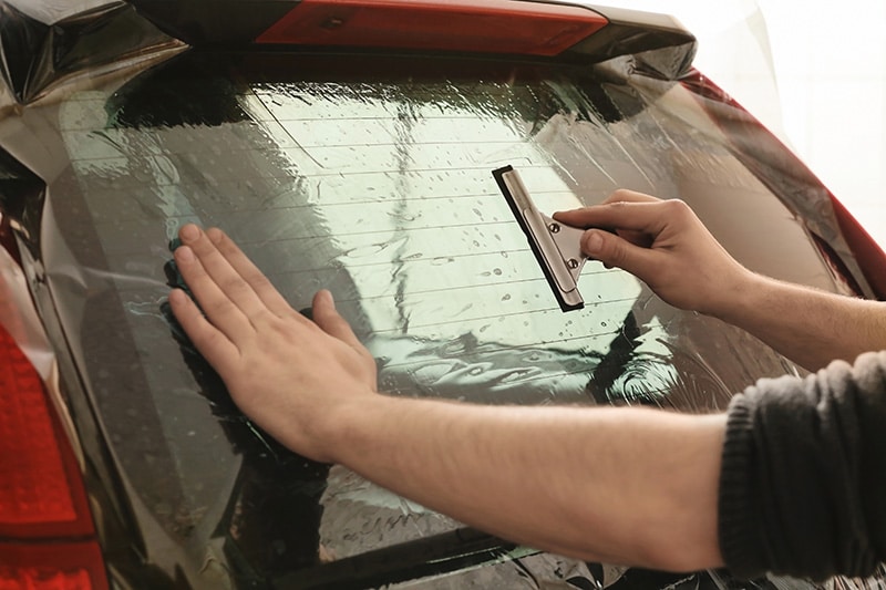 worker applying car window tint