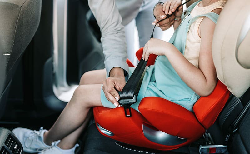 mom straps daughter into booster seat