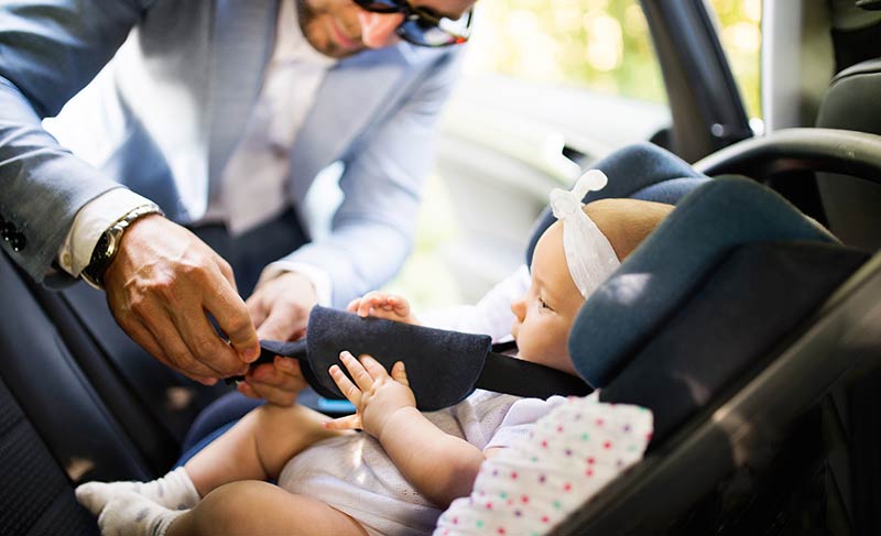 Dad fastens baby into carseat