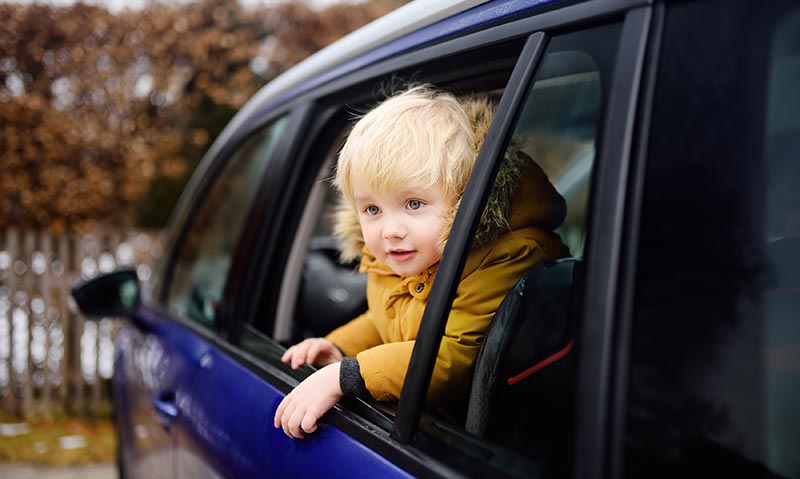 boy leans out of backseat of vehicle