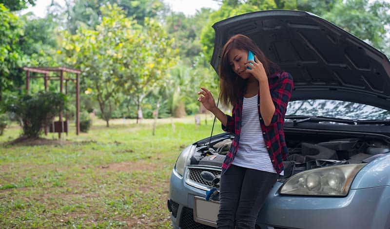 woman calls for help next to broken down car