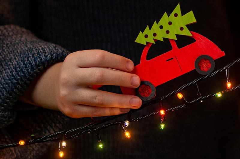 child slides toy car down strand of Christmas lights